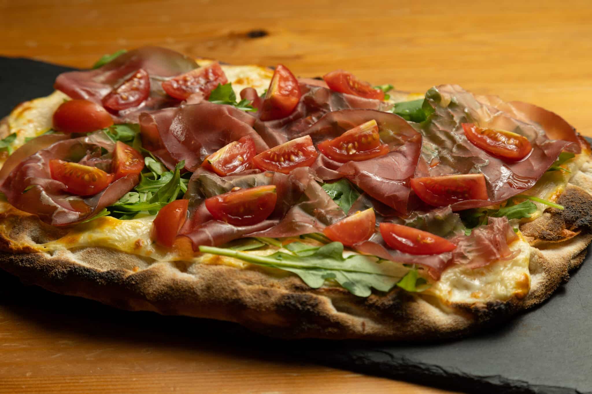 Pinsa Romana mit Tomaten Rucola und Jamon Schinken belegt