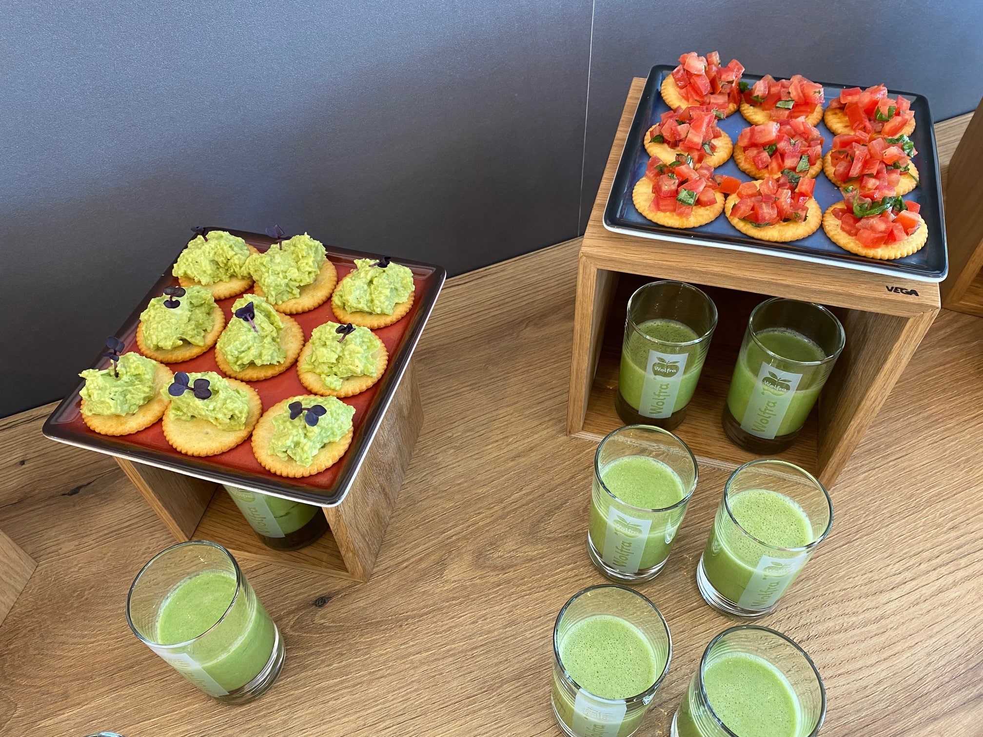 Zwei Platten mit Snacks und grünen Smoothies auf einem Holztisch.