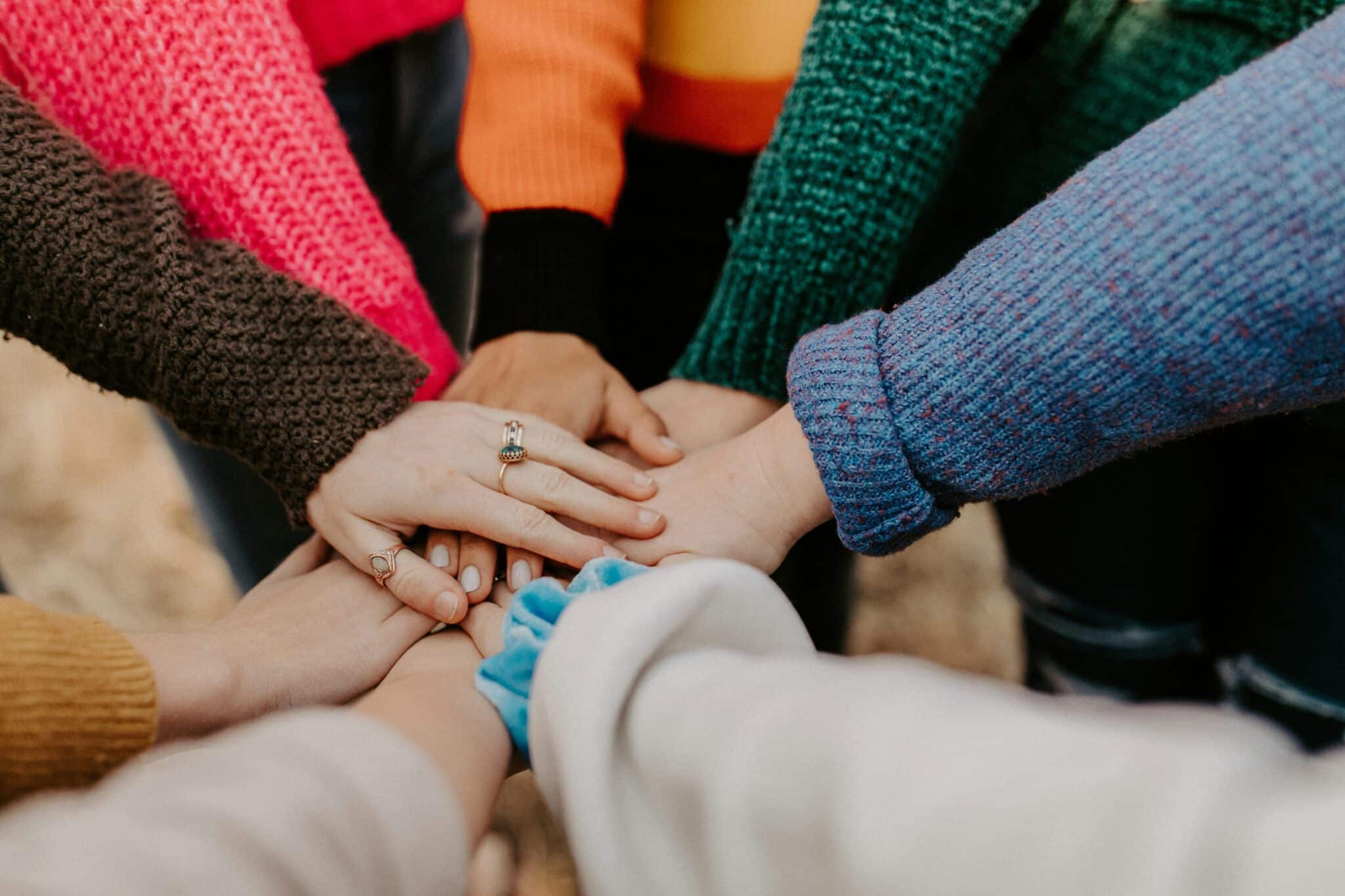 Eine Gruppe junger Menschen legt die Hände aufeinander (c) hannah busing unsplash