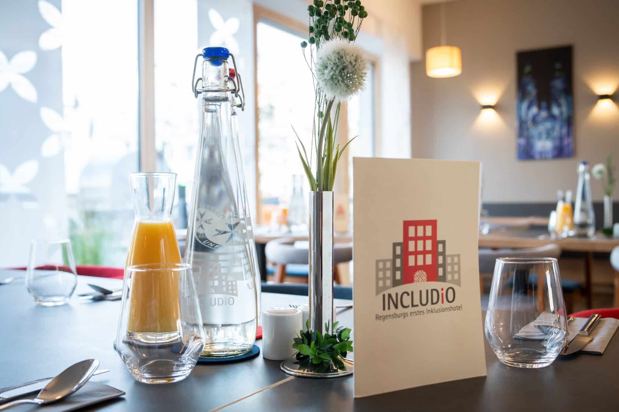 Tisch mit Meneralwasser, Saft und Speisekarte im Hotel INCLUDiO Regensburg